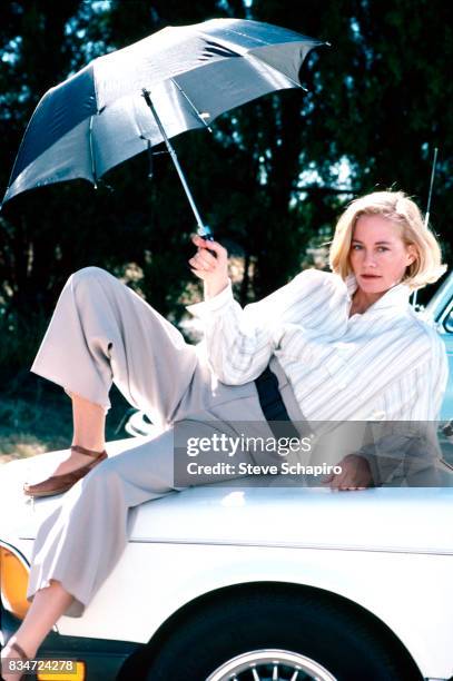 Portrait of American actress Cybill Shepherd as she reclines on the hood of a car, with an open umbrella in one hand, mid to late 1990s.