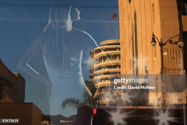 The Capitol Records building is reflected in a window with a photo of a model at the W Hollywood Hotel & Residences project over the Metro train...