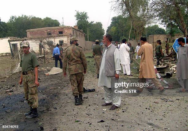 Pakistani soldiers and security officials gather at the suicide blast site in the garrison area of Bannu in North West Frontier Province on October...