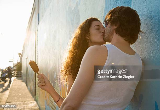 kissing couple leaning against wall - bisous photos et images de collection