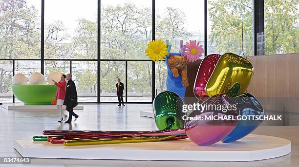 Visitors walk past the works "Tulips" , "Cat On A Clothesline" and "Bowl With Eggs " by US artist Jeff Koons during a press preview on October 29,...