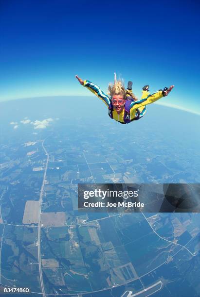 young skydiver in freefall above patchwork fields. - fallschirmsprung stock-fotos und bilder