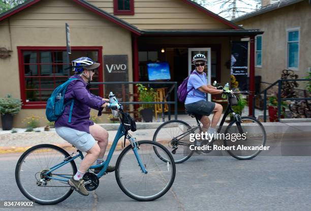 Two women ride their bicycles along Canyon Road, home to dozens of art galleries in Santa Fe, New Mexico.