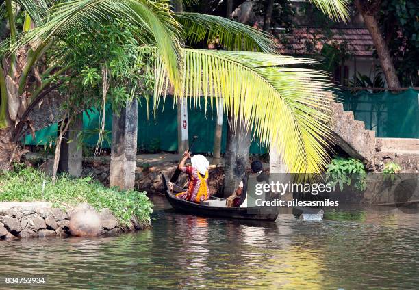 locals rowing under bridge, keralan backwater lagoon, kumarakom, kerala, southern india. - tapered roots stock pictures, royalty-free photos & images