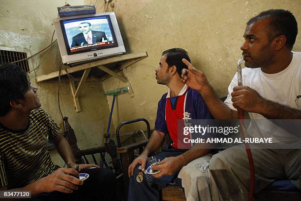 Iraqi men watch a repeat of the final US presidential debate between candidates Barack Obama and John McCain as they smoke waterpaipes at a coffee...
