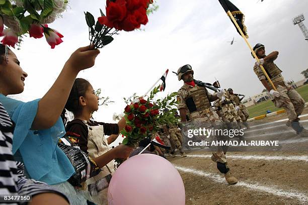 Iraqi children wave flowers as Iraqi soldiers parade at a football stadium in Wasit's provincial capital of Kut on October 29 during a ceremony for...