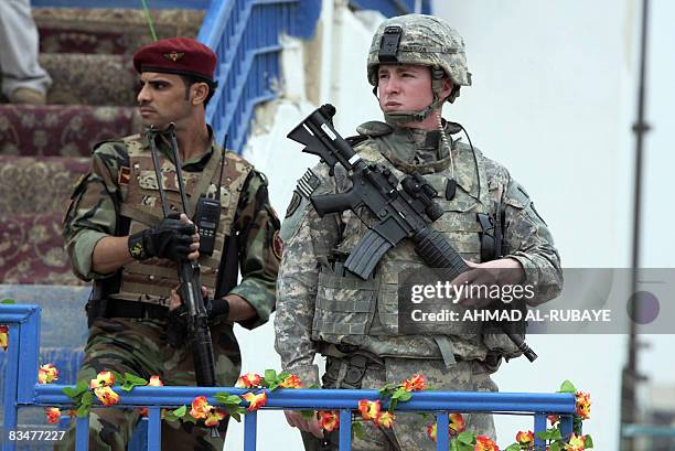 An Iraqi and an US soldier provide security for an armed forces parade at a football stadium in the Wasit provincial capital of Kut on October 29...