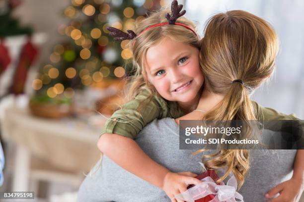 pretty little girl gives her mom a big hug on christmas eve - big xmas stocking stock pictures, royalty-free photos & images