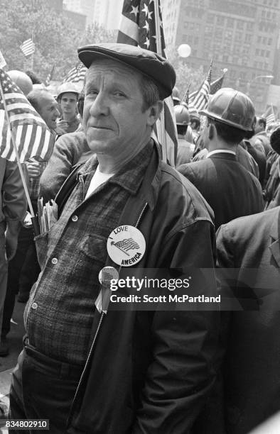 Downtown Manhattan May 1970: A older man stands proudly with construction workers, and war veterans, with an "I Love America" pin prominently...