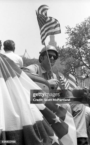 Downtown Manhattan May 1970: A construction worker sits with an American Flag in hand, along side his fellow construction workers, and war veterans...