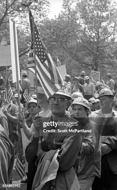 Downtown Manhattan May 1970: A middle aged man stands with an American Flag in hand, along side construction workers, and war veterans alike, to...
