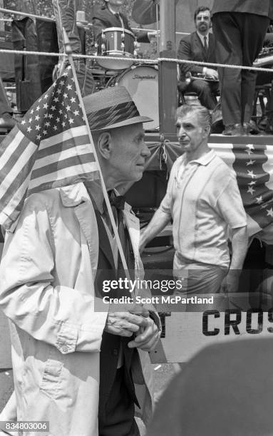 Downtown Manhattan May 1970: An older war veteran stands with an American Flag in hand, and protests Mayor Lindsey's decision to lower the American...