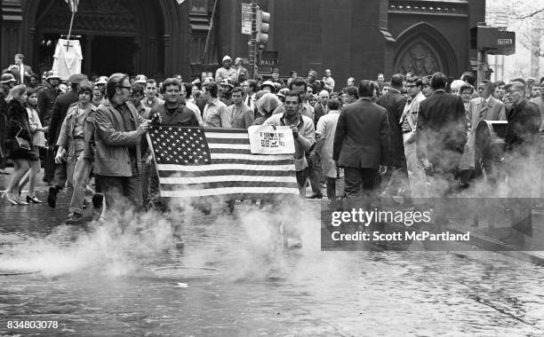Downtown Manhattan May 1970: A group of construction workers hold an American Flag in front of them, and march near Wall Street, protesting Mayor...