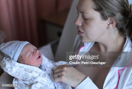 A Young woman holds her newborn baby in a safety grip in order to relieve him of winds. A Young woman holds her newborn baby in a safety grip in order to relieve him of winds.