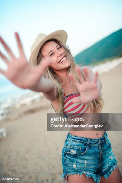 excited smiling female with outstretched arms to you at beach - american flag bathing suit women stock pictures, royalty-free photos & images