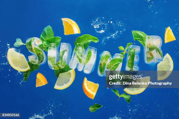 ice cube lettering with frozen mint leaves, lemon slices and oranges on a blue background with water splashes. text says summer - mint freshness stock pictures, royalty-free photos & images