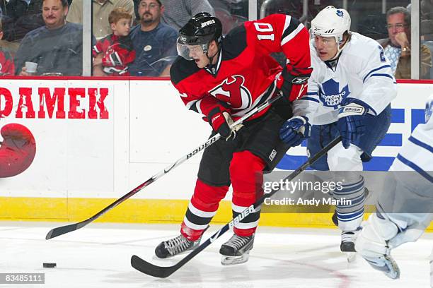 Matt Halischuk of the New Jersey Devils is challenged for possession of the puck by Luke Schenn of the Toronto Maple Leafs for possession of the puck...