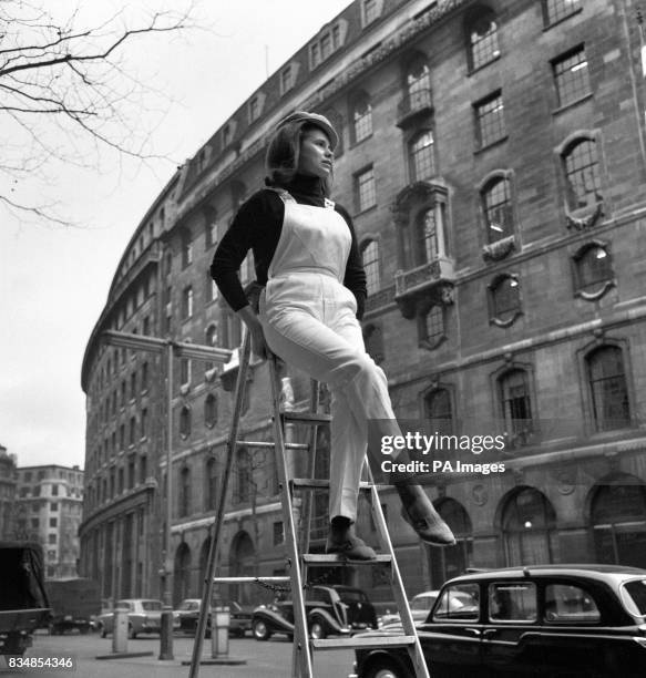 Up a ladder wearing the latest in bib and brace overalls is Suzanne Kennedy in The Aldwych, London. The new overalls are by Lybro of Liverpool.