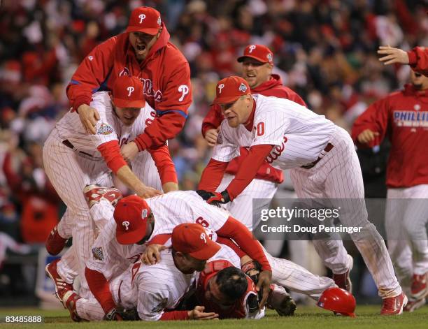 Chase Utley, Ryan Howard and Geoff Jenkins of the Philadelphia Phillies pile on top of closing pitcher Brad Lidge and catcher Carlos Ruiz after they...