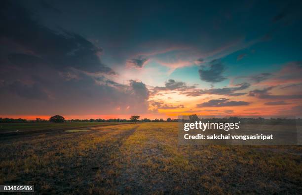 scenic view of field against dramatic sky at sunset - day and night image series stock pictures, royalty-free photos & images