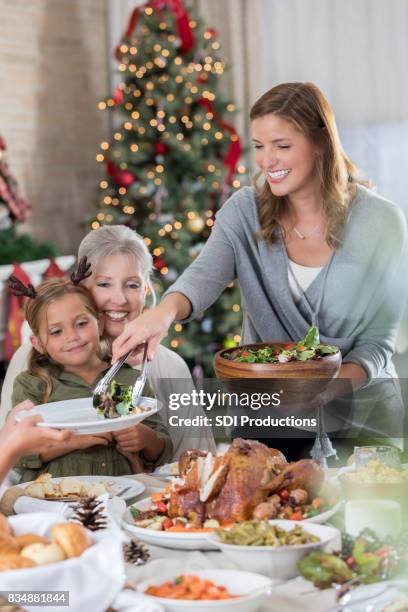 mid adult woman serves salad at christmas dinner - perfection salad stock pictures, royalty-free photos & images