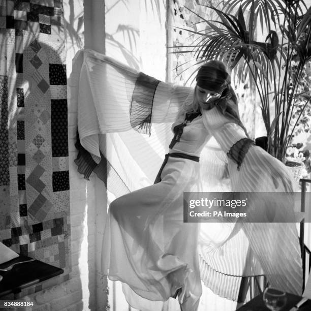 Penny Slinger is seen wearing a blue and white pleated cape over a blue and white embroidered chiffon dress at the Thea Porter show.