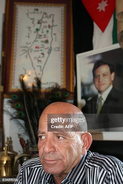 Palestinian Zuher Hamdan sits under a portrat of Jordan's King Abdullah and the Jordanian flag during an interview with AFP at his house in the town...