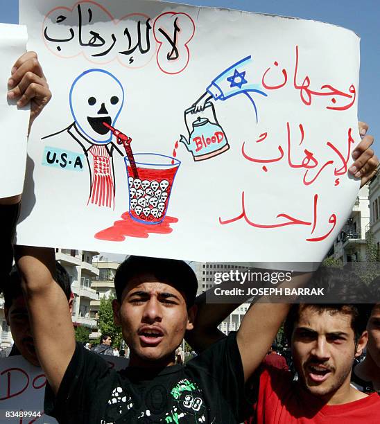 Syrian youth holds an anti-US and Israel placard with the Arabic writing 'No for terrorism' and 'two faces for the same terrorism' during a...