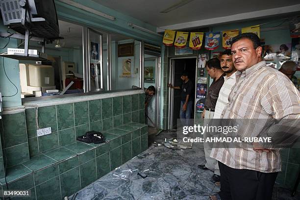 Iraqi men stand in a shop that was damaged in a car bomb that killed one and wounded five in a Baghdad market on October 30, 2008. Baghdad wants to...