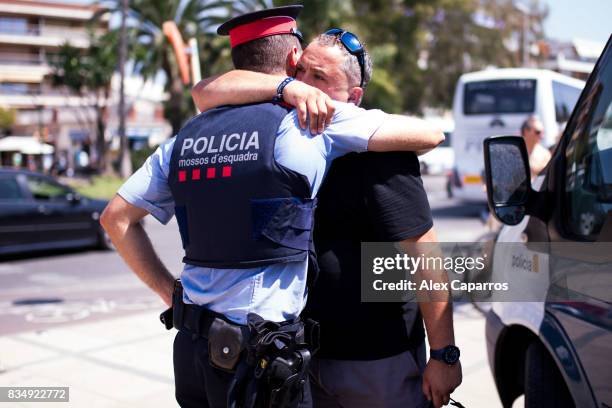 Man embraces a police officer on the spot where five terrorists were shot by police on August 18, 2017 in Cambrils, Spain. Fourteen people were...