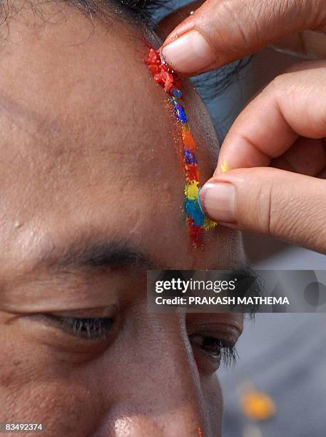 Nepalese women apply a seven-colour Tika - religious marking - to their brother's forehead on the occasion of Bhai Tika - brothers' worship - on the...