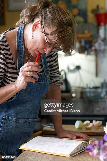 woman reads recipe book in kitchen - rezeptbuch stock-fotos und bilder