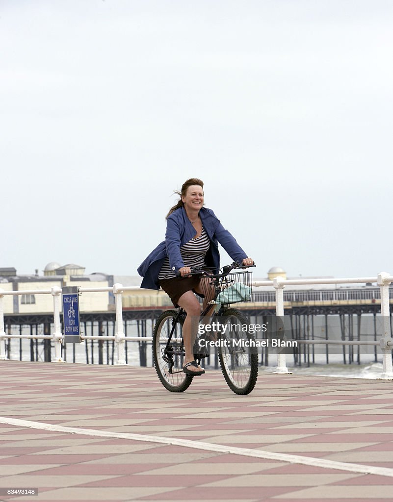 Woman smiling and cycling by the sea