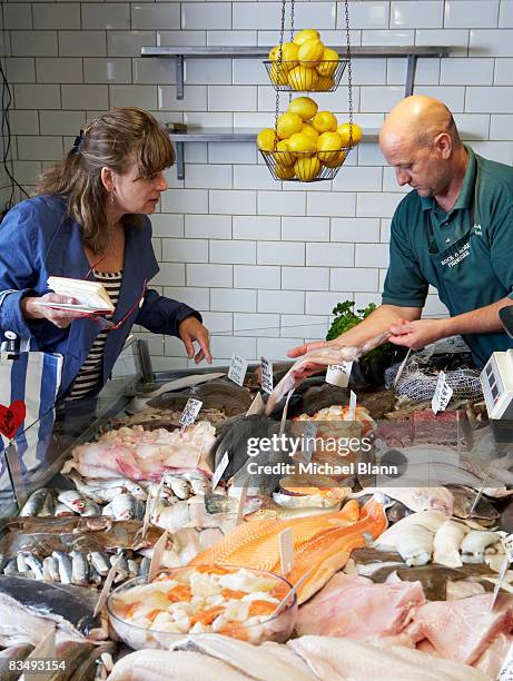 woman selecting fish from shop owner - pescivendolo foto e immagini stock