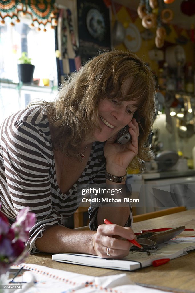 Woman smiling whilst talking on phone in kitchen