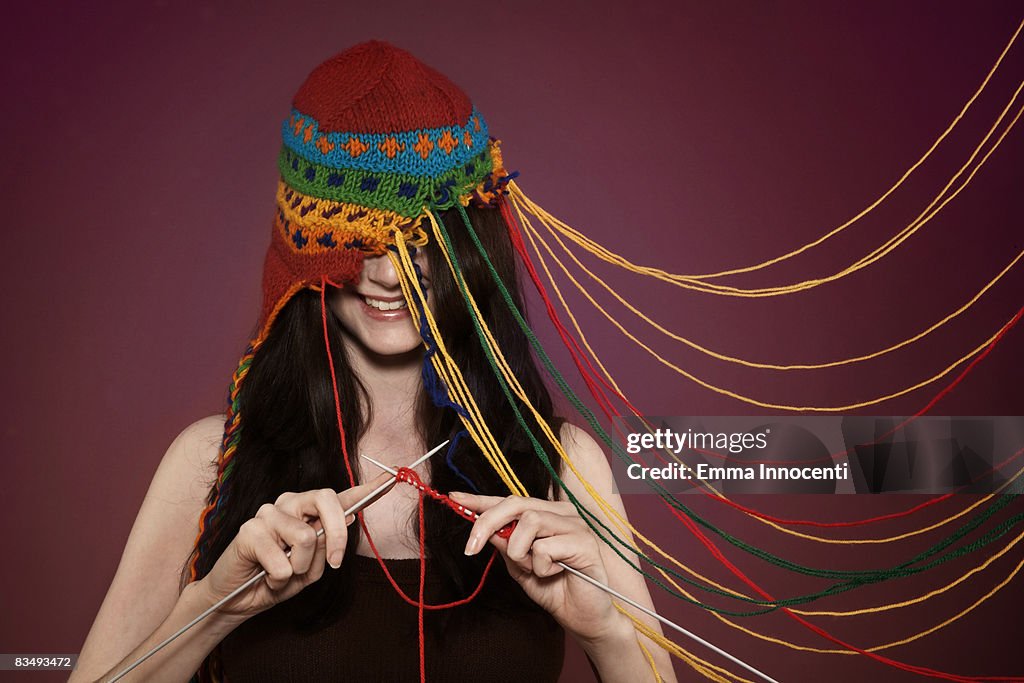Lady knitting on her own hat