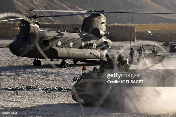 Made M113 armoured personnel carrier from the Afghan National Army drives past a US Army CH-47 Chinook heavy-lift helicopter at Forward Operating...