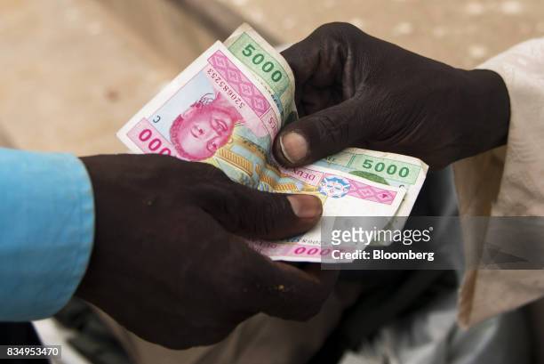 Man pays with a vendor with Central African franc banknotes on a street in N'Djamena, Chad, on Wednesday, Aug. 16, 2017. African Development Bank and...
