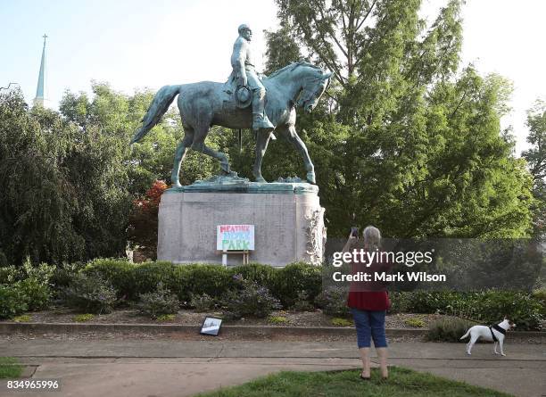 Homemade sign that says Heather Heyer Park rests at the base of the statue of Confederate Gen. Robert E. Lee that stands in the center of...