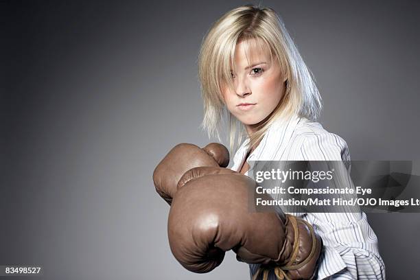 businesswoman wearing boxing gloves - boxing glove coloured background stock pictures, royalty-free photos & images