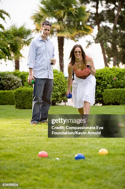 couple playing bocce ball on lawn. - bocce ball stock pictures, royalty-free photos & images