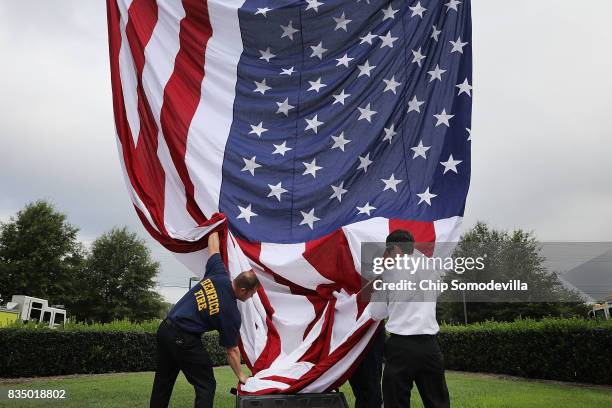 Firefighters from Henrico and Chesterfield counties raise a large U.S. Flag in front of Saint Paul's Baptist Church ahead of the funeral for Virginia...