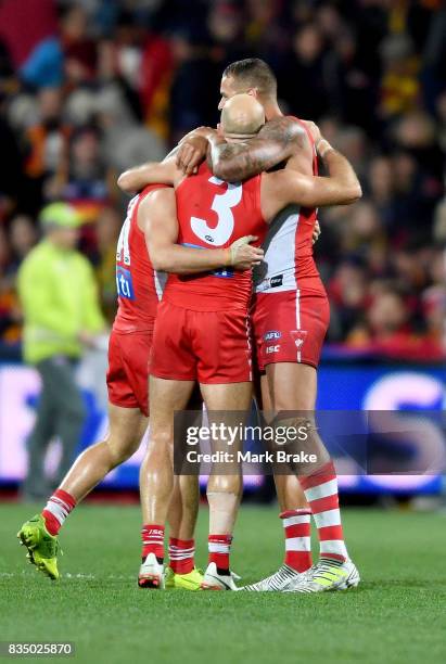 Tom Papley, Jarrad McVeigh and Buddy Franklin embrace at the final siren during the round 22 AFL match between the Adelaide Crows and the Sydney...