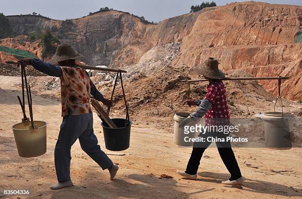 Two women carry water to plant trees at a hill damaged by over-exploitation of ceramic earth, at the Yuantan Township, since many ceramics companies...