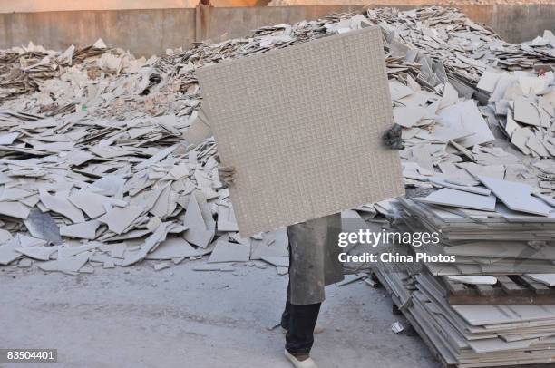 Worker carries a tile in a workshop of Monalisa Ceramics Company which was shifted from China's largest ceramics production center Foshan due to...