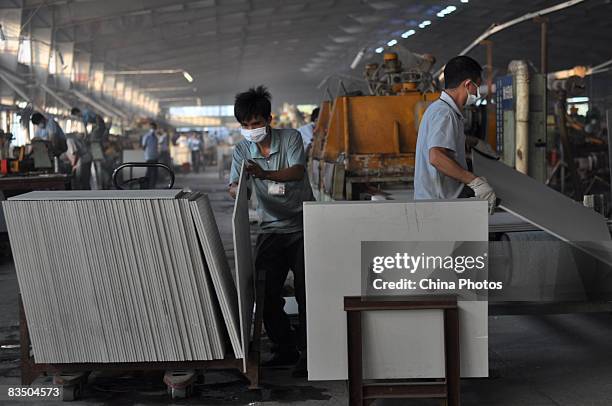 Two workers wearing masks moves tiles to polish in a workshop of Monalisa Ceramics Company which was shifted from China's largest ceramics production...