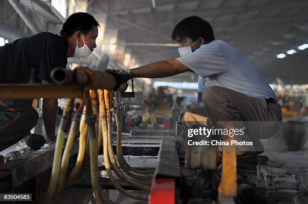 Two workers wearing masks labour at a tile product line in a workshop of Monalisa Ceramics Company which was shifted from China's largest ceramics...