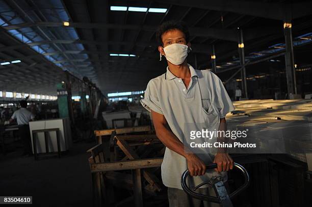 Worker wearing a mask transports tile in a workshop of Monalisa Ceramics Company which was shifted from China's largest ceramics production center...