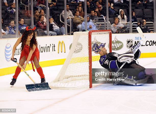 Jason LaBarbera of the Los Angeles Kings stretches while a devil clad girl cleans the ice in a 0-4 loss to the Vancouver Canucks during the third...