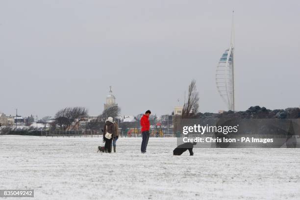 The Spinnaker Tower stands over dog walkers out on Southsea Common in Portsmouth as heavy snowfall hits the UK.